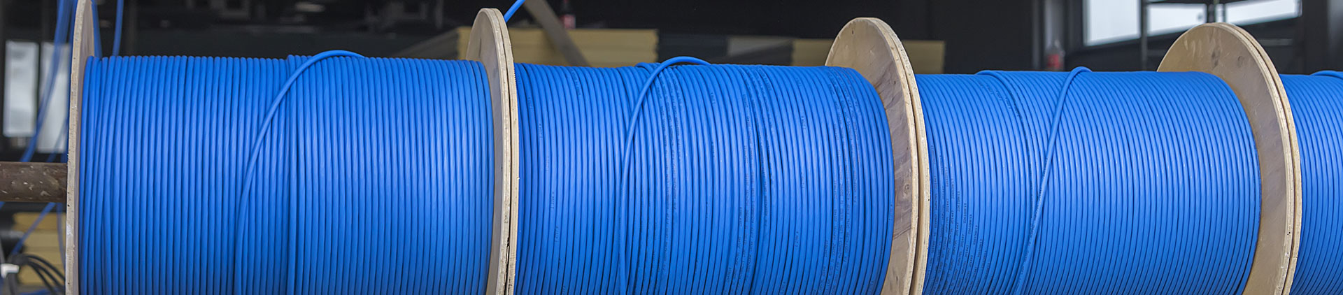 Close-up view of large spools of blue bulk Ethernet cable, neatly wound and ready for use, in an industrial setting, showcasing durable and high-quality copper wiring.