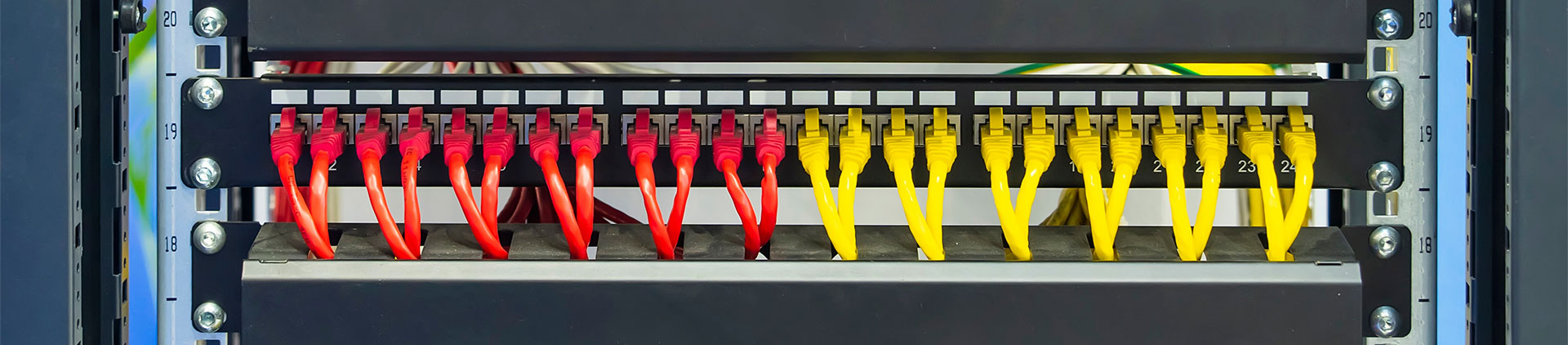 A neatly organized patch panel featuring vibrant yellow and red Cat6A patch cables connected to network ports, providing a clear and efficient setup for high-speed data transmission.
