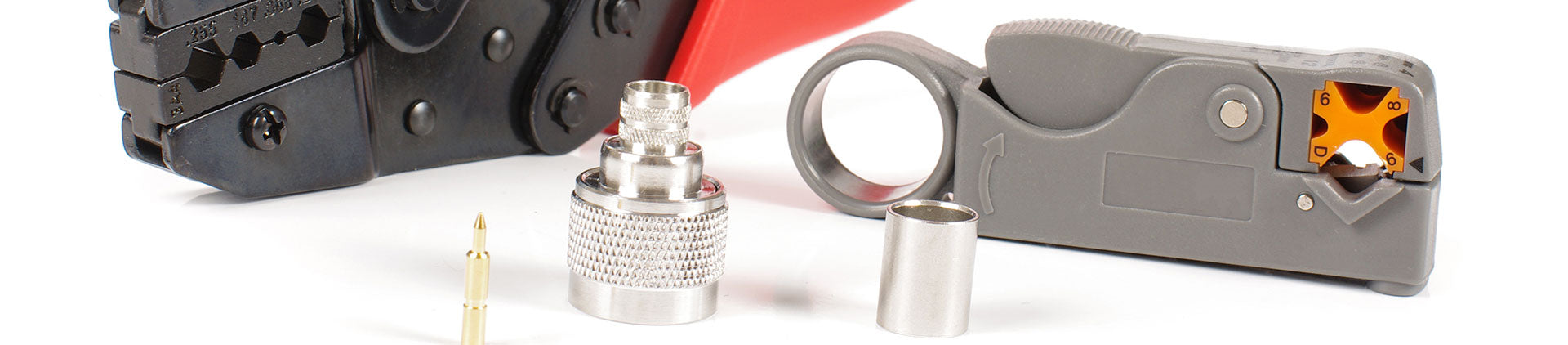 Close-up image of coaxial cable tools and components, including a crimping tool, cable stripper, and metal connectors, displayed on a white background.