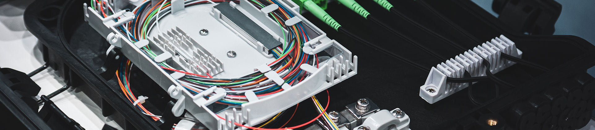 A close-up view of a fiber optic splice tray, neatly arranged with colorful fiber cables and connectors. The organized layout highlights the precision and complexity involved in modern networking and fiber optic systems.