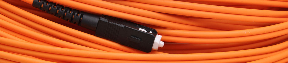A close-up image of an orange fiber optic patch cable coiled neatly, showcasing its smooth, durable outer sheath and a black connector with a white tip.