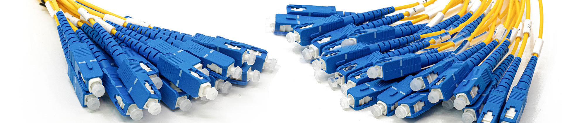 Close-up image of multiple yellow fiber optic patch cables with blue SC connectors, neatly arranged, highlighting their precision design and suitability for high-speed network connections.