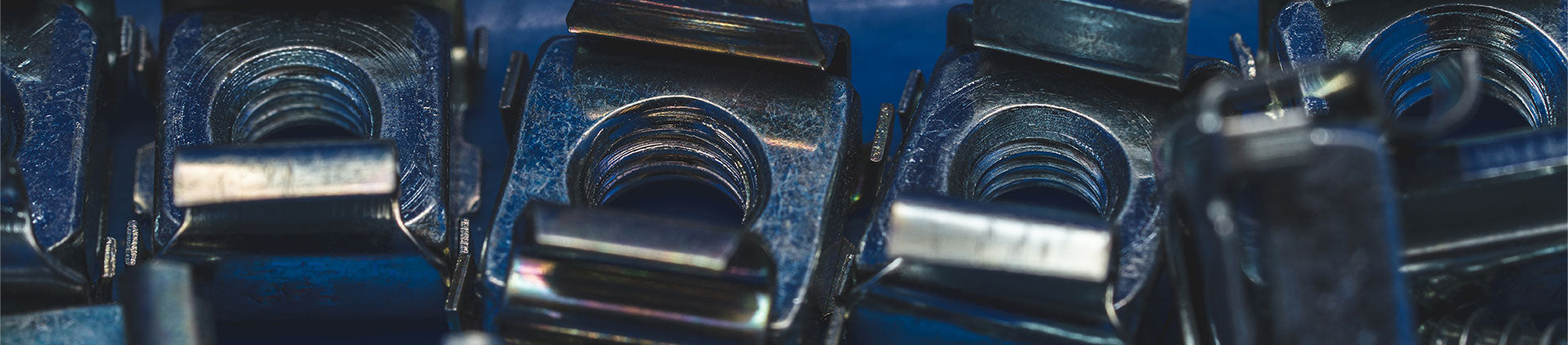 Close-up view of metallic cage nuts and clips used for securing hardware components in server racks or enclosures, showcasing their sturdy design and precision engineering.