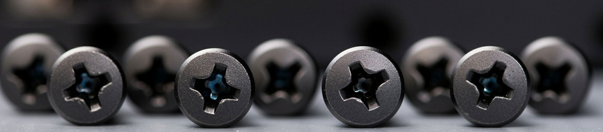 Close-up of black Phillips-head rack screws arranged neatly on a surface.