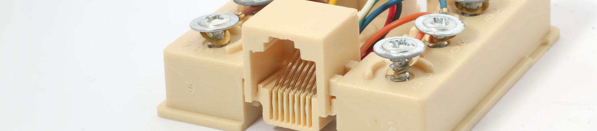 A close-up view of a beige surface mount box with exposed internal wiring and connection screws.