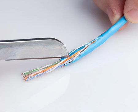 Technician trimming a blue cable with specialized knife