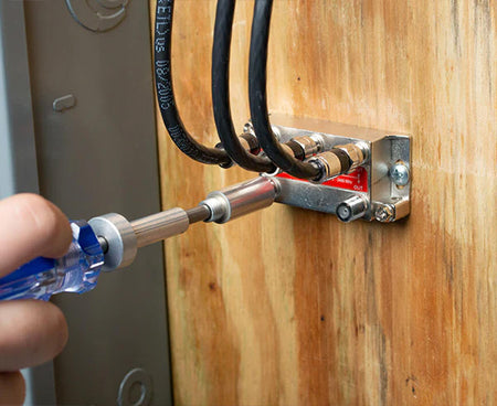 The process of securing a wire to a wooden panel with the 7 1/2" Terminator Tool