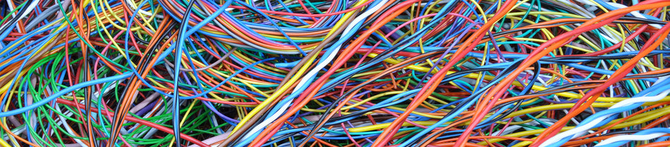 Close-up image of a tangled collection of colorful network cables, including blue, red, orange, green, and yellow wires, showcasing their vibrant insulation and variety.