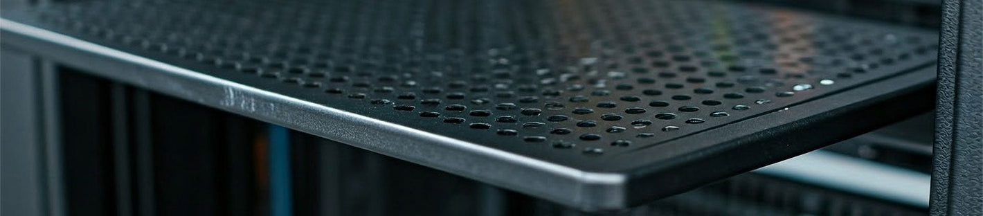 Close-up of a black metal network rack shelf with round perforations, providing ventilation. 