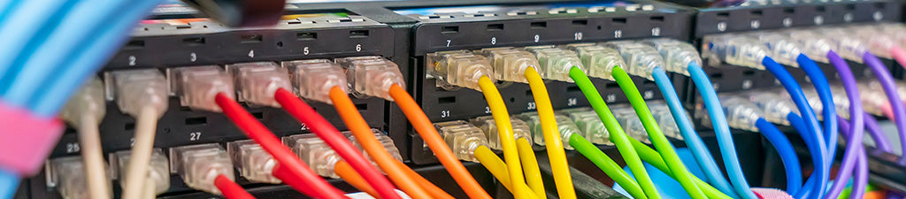 Brightly colored ethernet patch cables installed in a rack mounted patch panel.