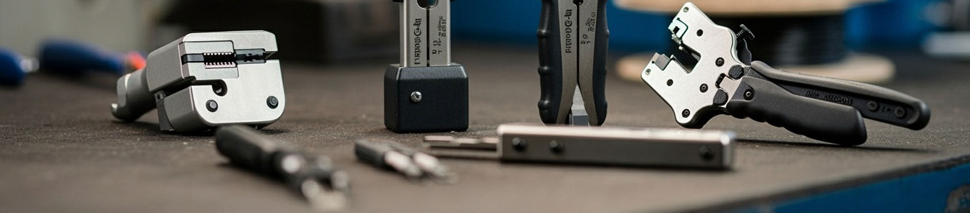 Close-up of various high-quality fiber optic stripping tools arranged on a workbench, designed for precision and ease of use in fiber cable preparation.