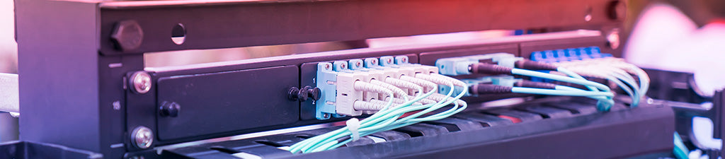 A fiber patch panel in a network rack with connected fiber patch cables.