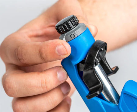 A hand demonstrating the adjustment mechanism on the Round Cable Strip & Ring Tool