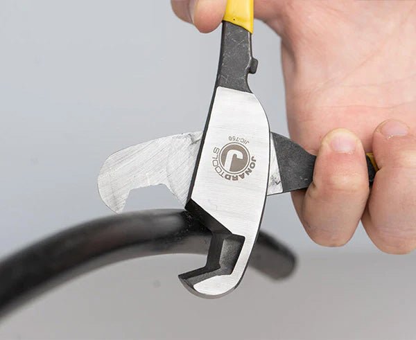 A hand gripping the 3/4" COAX cable cutter with yellow and black handles