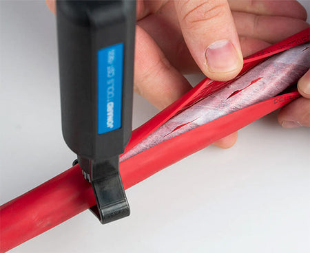Fiber optic technician neatly trimming a red cable with a red and black tool from the kit