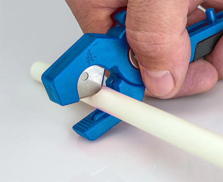 Professional using the kit's blue pipe cutter on a section of tubing