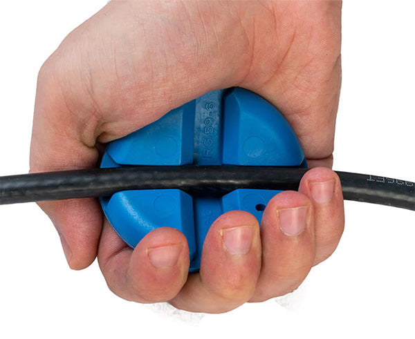 Hand holding a blue fiber optic cable with cable grip puck from the prep kit