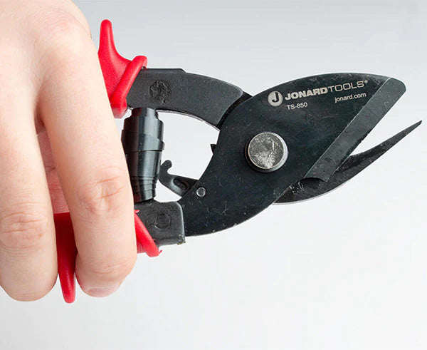 Close-up of tabbing shears with red and black grips in a user's hand