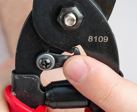 A person using tabbing shears with red and black handles for precision cutting
