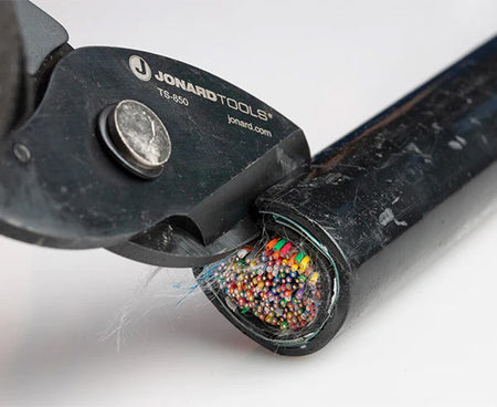 Detailed view of tabbing shears' cutting head with colorful wire insulation in the background