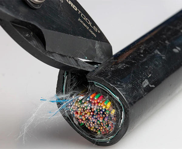Tabbing shears positioned next to a multicolored cable, showcasing the tool's use