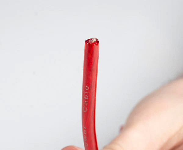 User cutting a red wire with the handheld cable cutter
