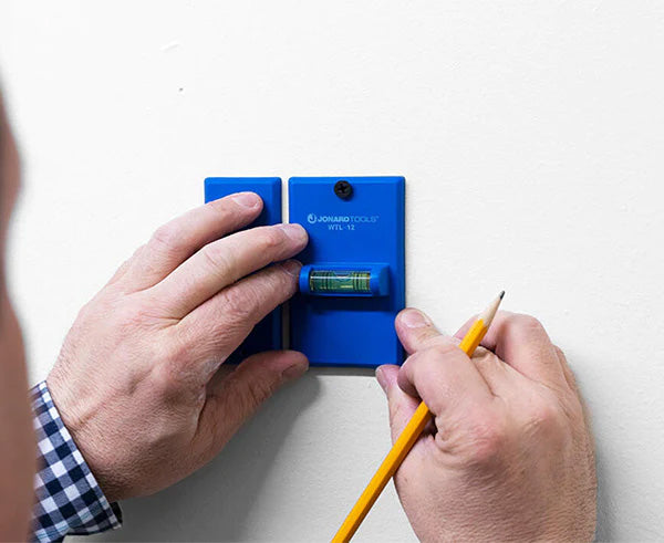 Electrician utilizing the wall box template to mark the cutout for a box