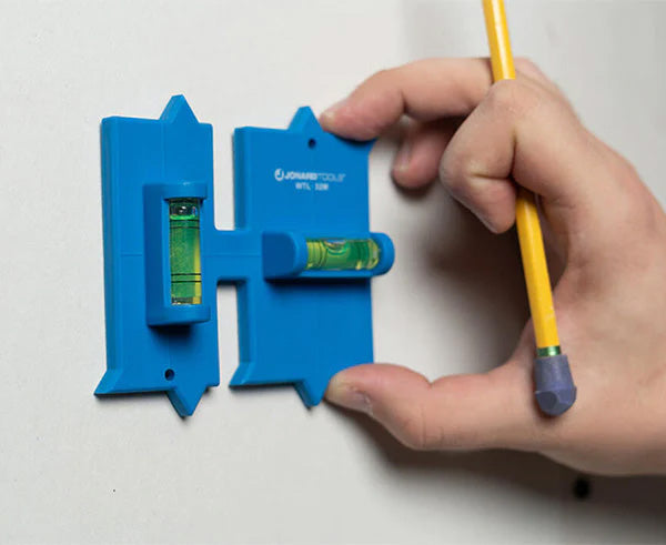 A person marking a wall with a pencil using the Wall Box Template for precise installation