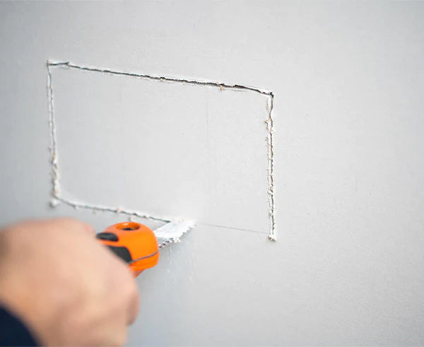 Using a drywall saw to make adjustments to a wall during the installation of a non-metallic electrical box