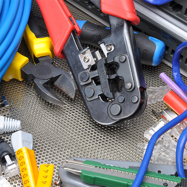 Close-up of crimping tool and various tools on a metallic surface