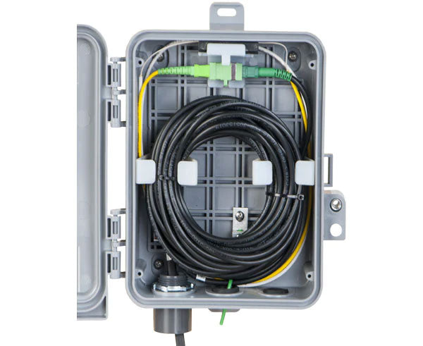 Outdoor wall mount fiber slack/demarcation enclosure showing cable placement.
